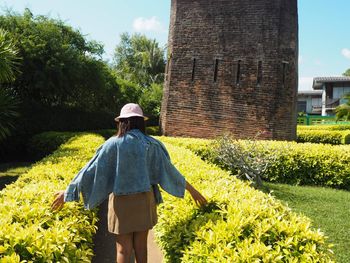 Rear view of woman standing by plants on field