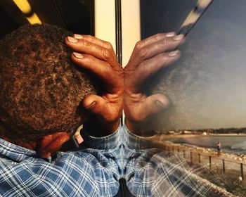 Close-up of senior man with hand on head by glass window in bus