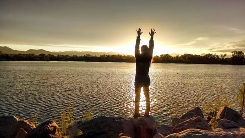 Silhouette person on lake against sky during sunset