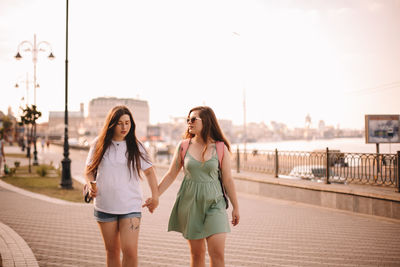 Full length of young woman in city against sky