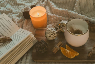 Christmas decorations with lights, hot drink, fruits and a good book