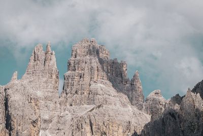 Low angle view of rocks against cloudy sky