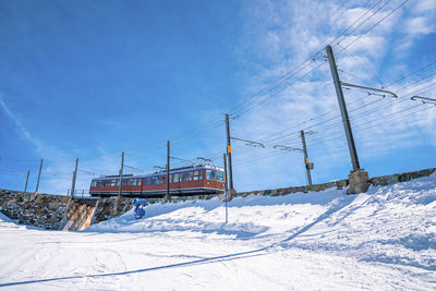 Red train moving towards gornergrat station on mountain against blue sky