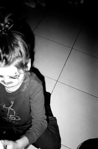 Rear view of girl sitting on floor at home