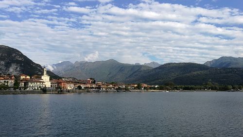 Town by sea against cloudy sky