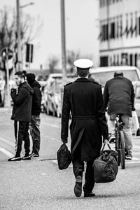 Rear view of people walking on street in city