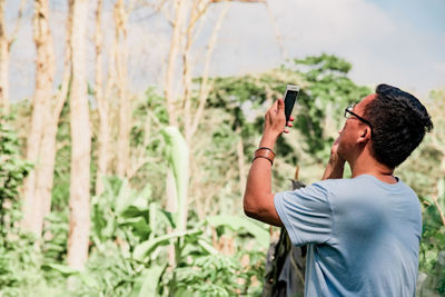 A man taking pictures with his smartphone in a forest