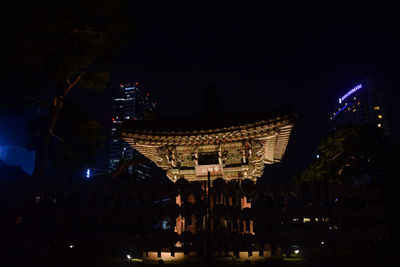 Low angle view of illuminated city against sky at night