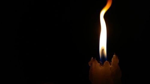 Close-up of lit candle against black background