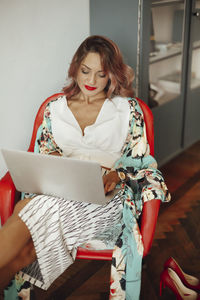 Woman using laptop while sitting in chair