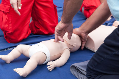 Midsection of trainer with cpr dummy explaining to paramedics