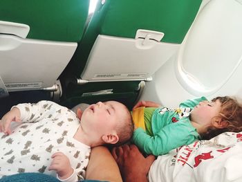 High angle view of children sleeping on laps of parents in airplane