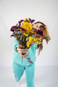 Unaltered candid emotional portrait of young happy blonde long hair woman with flower bouquet on