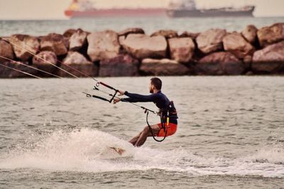 Full length of man surfing by sea shore against sky