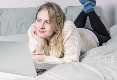 Portrait of woman lying on bed at home