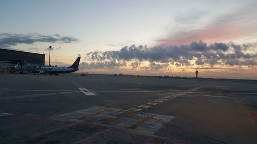 Airplane on runway against sky during sunset