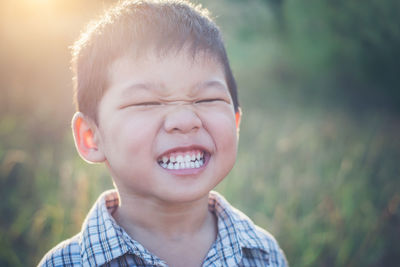 Close-up portrait of happy boy clenching teeth during sunny day