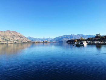 Scenic view of sea and mountains against clear blue sky