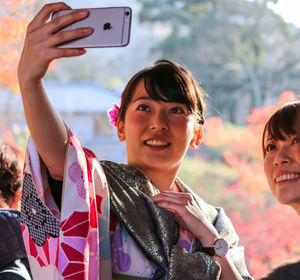 Portrait of smiling woman photographing with mobile phone