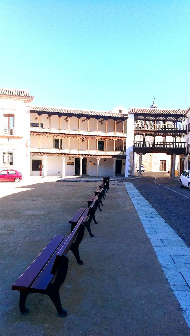 EMPTY STREET AMIDST BUILDINGS AGAINST BLUE SKY