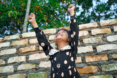 Full length of woman standing against brick wall