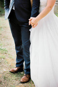 Low section of bride holding bouquet