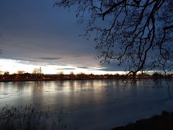 Silhouette trees by lake against sky during sunset