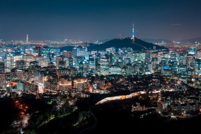 Illuminated cityscape against clear sky at night