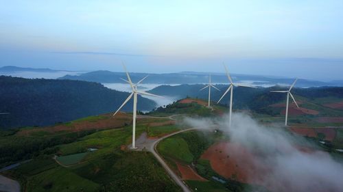 Windmills on field against sky