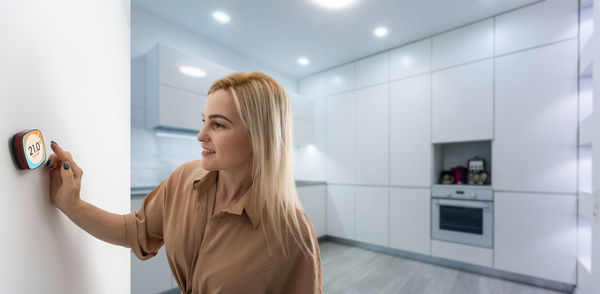 Woman using smartphone monitor to control home connectivity interface