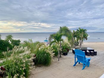 Deck chairs on beach against sky