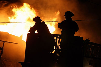 Silhouette people against fire at night