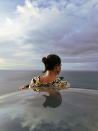 Girl on beach against sky exiting a car