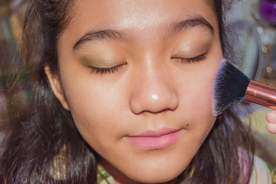 Portrait of a young girl getting make up applied to her face 