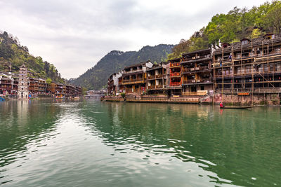 View of buildings at waterfront against cloudy sky