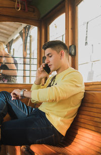 Young man using smart phone while sitting on seat