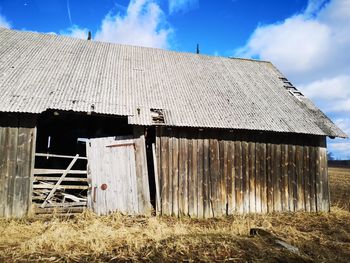 Old abandoned house on field against sky