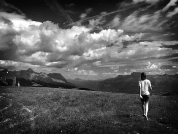 Rear view of woman standing on mountain against sky