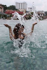 Woman splashing water in swimming pool