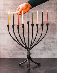 Cropped image of a hand lighting candles on menorah for hanukkah.