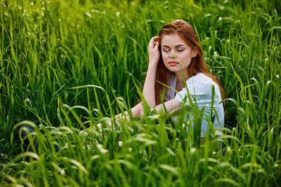 Portrait of young woman sitting on grassy field