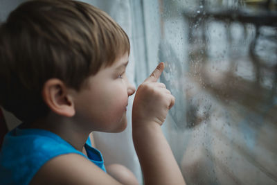 Portrait of boy looking through glass window