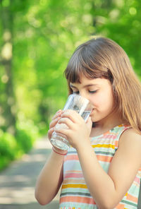 Young woman drinking milk while standing outdoors