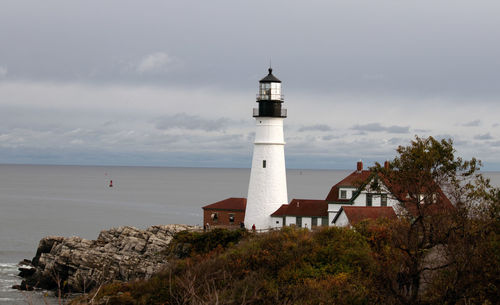 Lighthouse by sea against sky