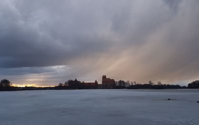 Buildings by city against sky during sunset