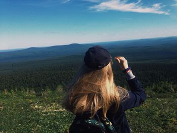 Rear view of woman looking at field against sky