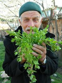 Portrait of old man holding herbs