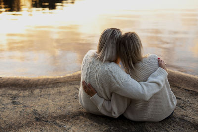 Female couple sitting at lake