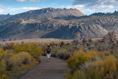 Rear view of woman on footpath amidst mountains against sky
