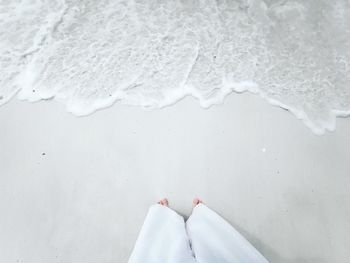Low section of woman standing on sea shore